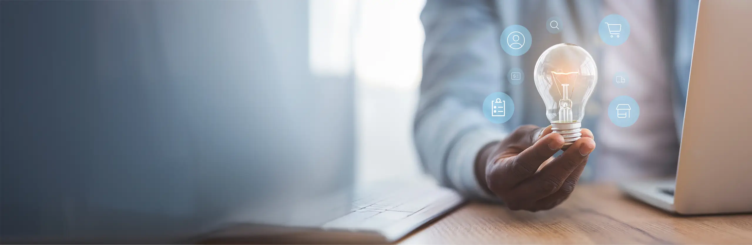 Mann vor Laptop hält eine Glühbirne